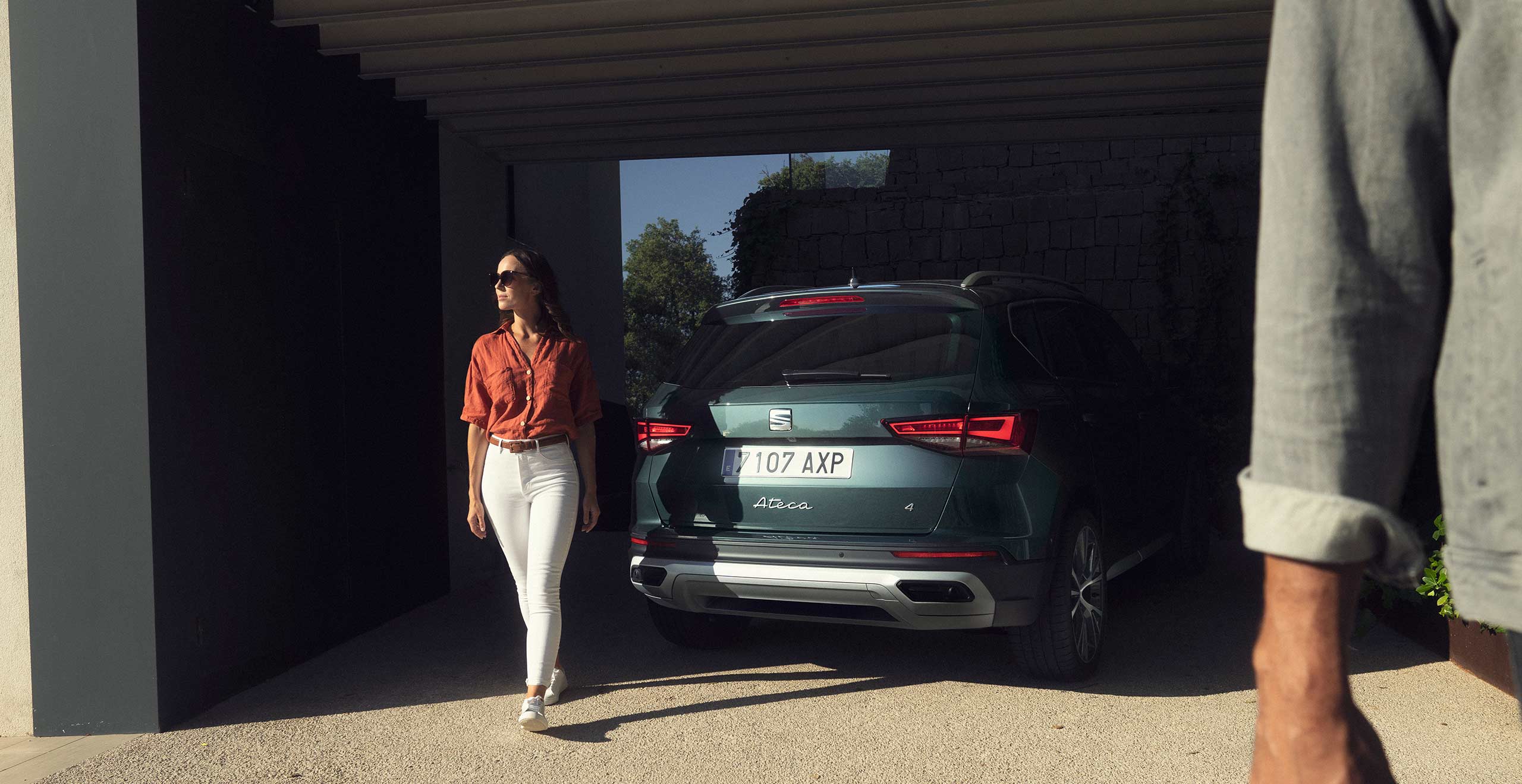 Side view of a red SEAT Leon Sportstourer 2024 in a car park, woman looking at the front