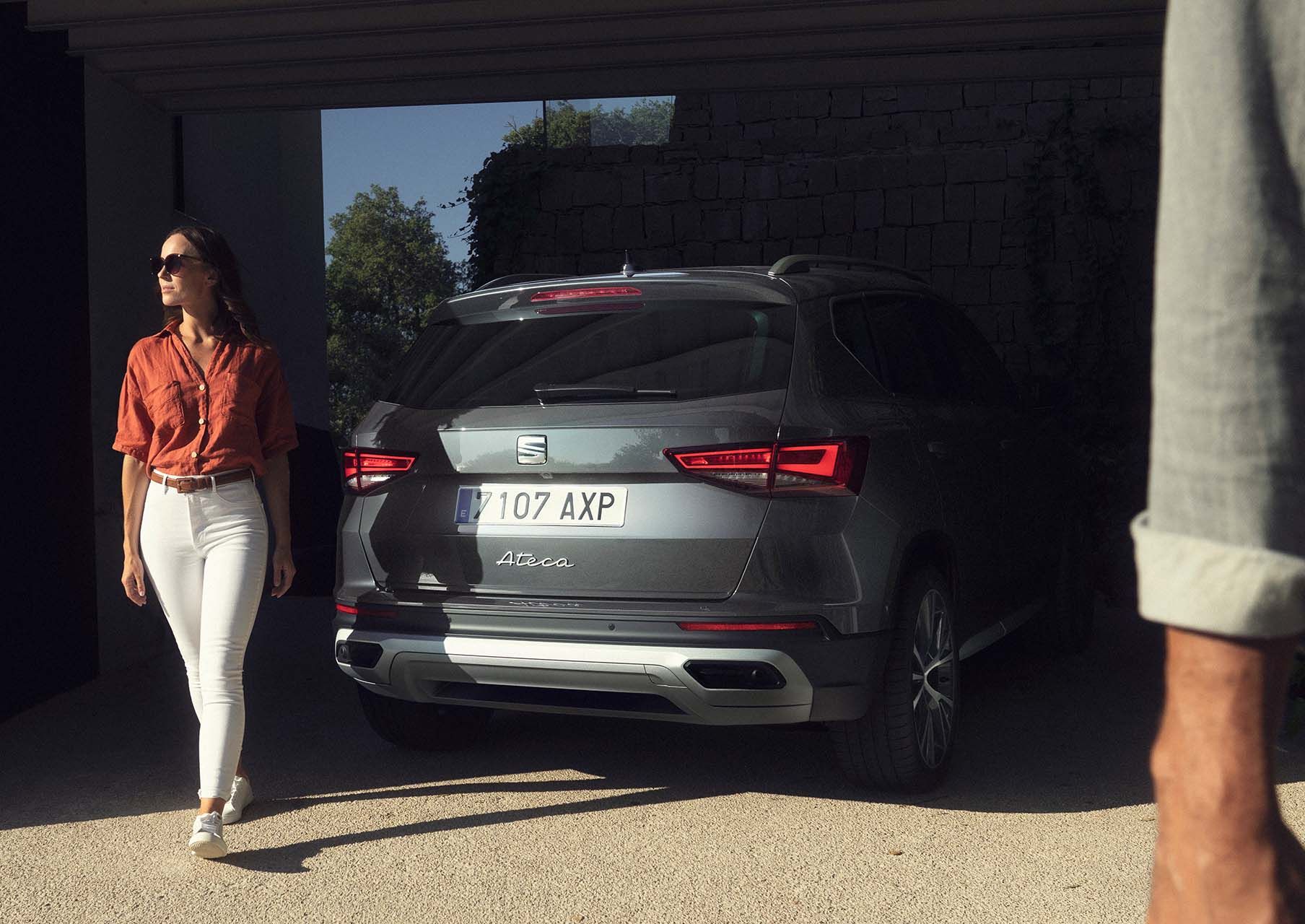 woman standing next to the seat ateca graphite grey with full rear led lights