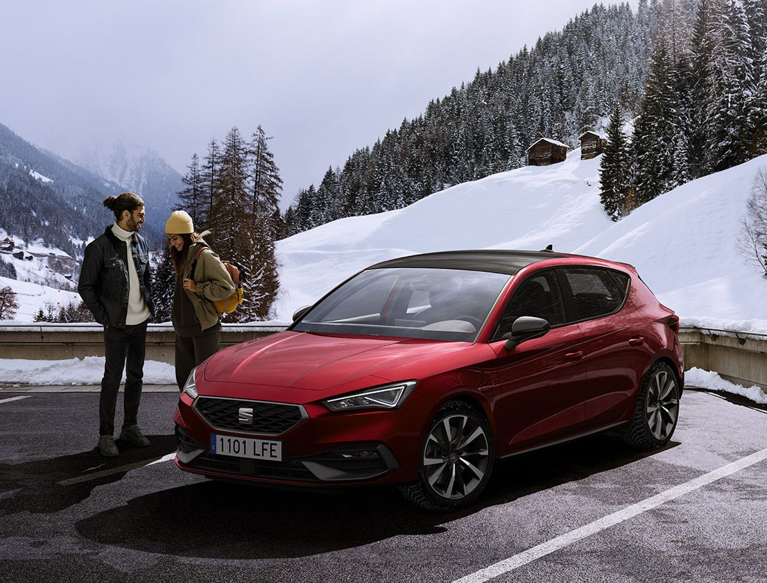 couple talking next to a seat leon desire red colour in a snowy mountain