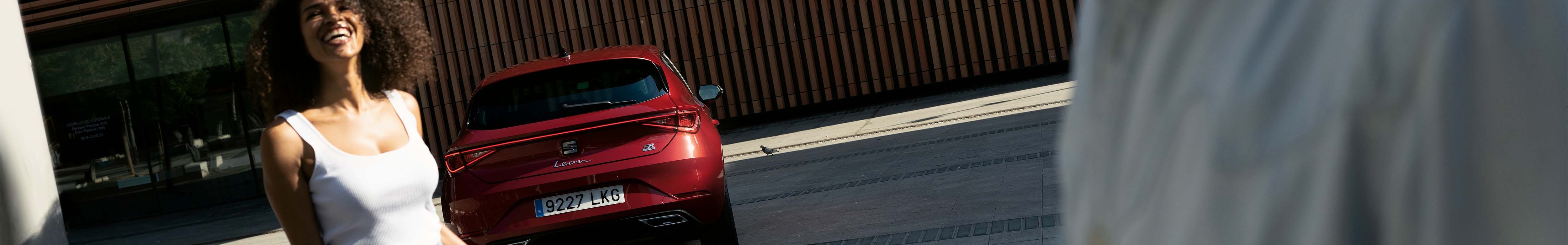 Seat leon parked with a couple nearby, ready to debunk common myths about hybrid electric vehicles.