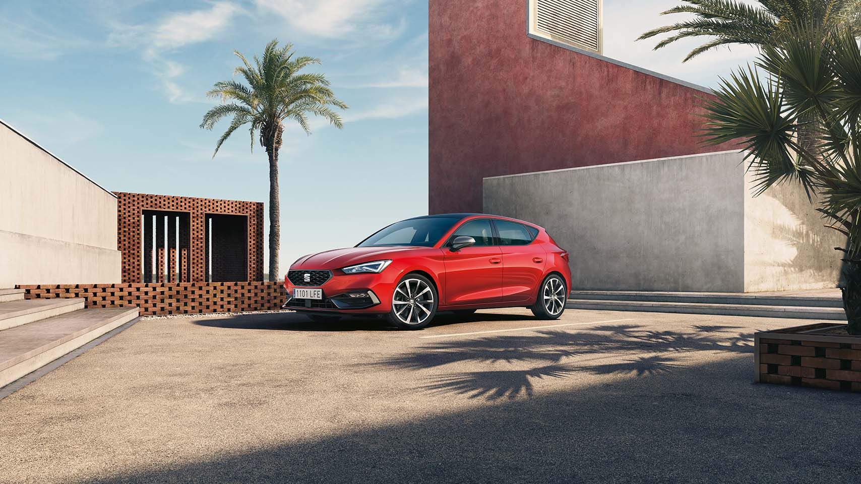 Mild hybrid electric vehicle, seat leon in red, blue skies and cement car park